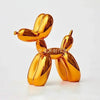 A golden resin balloon dog sculpture with a whimsical design, used as home or office decor.