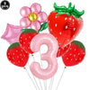 A set of nine pink and red balloon decorations including a strawberry shape and the number three for a party kit