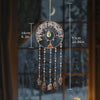 A hanging crystal tree of life sun catcher with branches and dangling crystals, displayed against a blurred window background