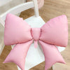A pink balloon bow set used as a birthday banner decoration on a white table.