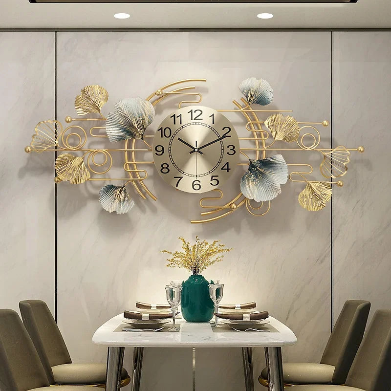 A decorative metal ginkgo leaf wall clock with a round face hangs on a light gray wall above a table.