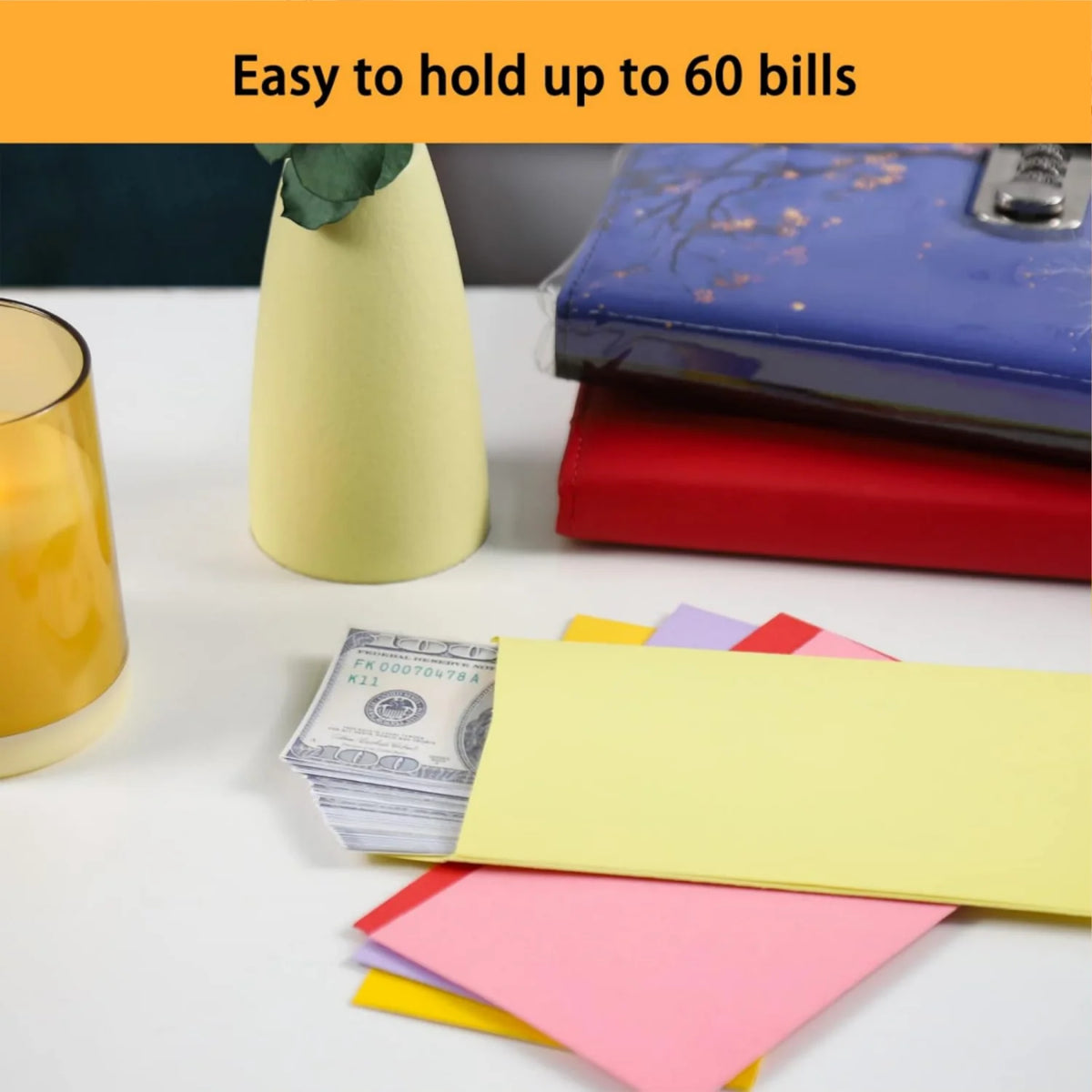 Colorful side-loading cash envelopes stacked on a white surface next to a yellow glass and a blue wallet.