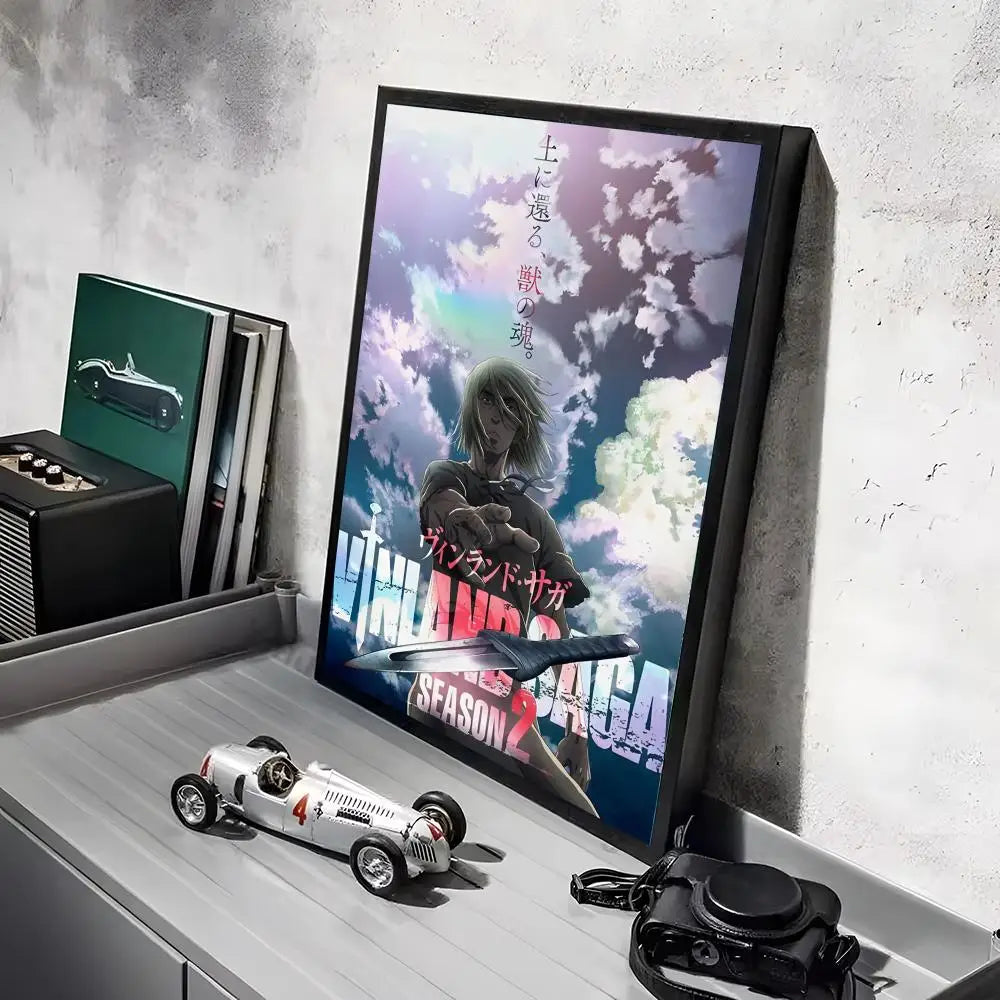 A framed poster of the Vinland Saga anime featuring a character against a dramatic sky, displayed on a shelf.