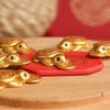 A collection of gold turtle charms resting on a red felt pad on a wooden surface.