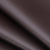 Close-up of a dark brown self-adhesive PU leather repair patch being applied to a material.