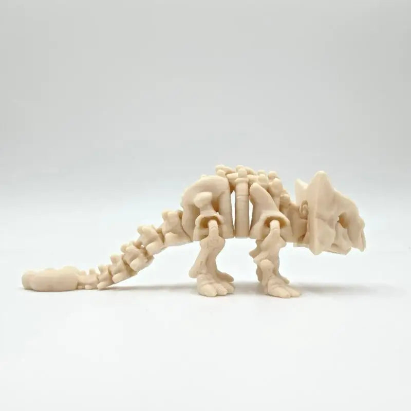 A light beige 3D printed dinosaur skeleton model for desktop display.