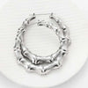 Silver bamboo hoop earrings with a textured, organic design displayed on a white surface.