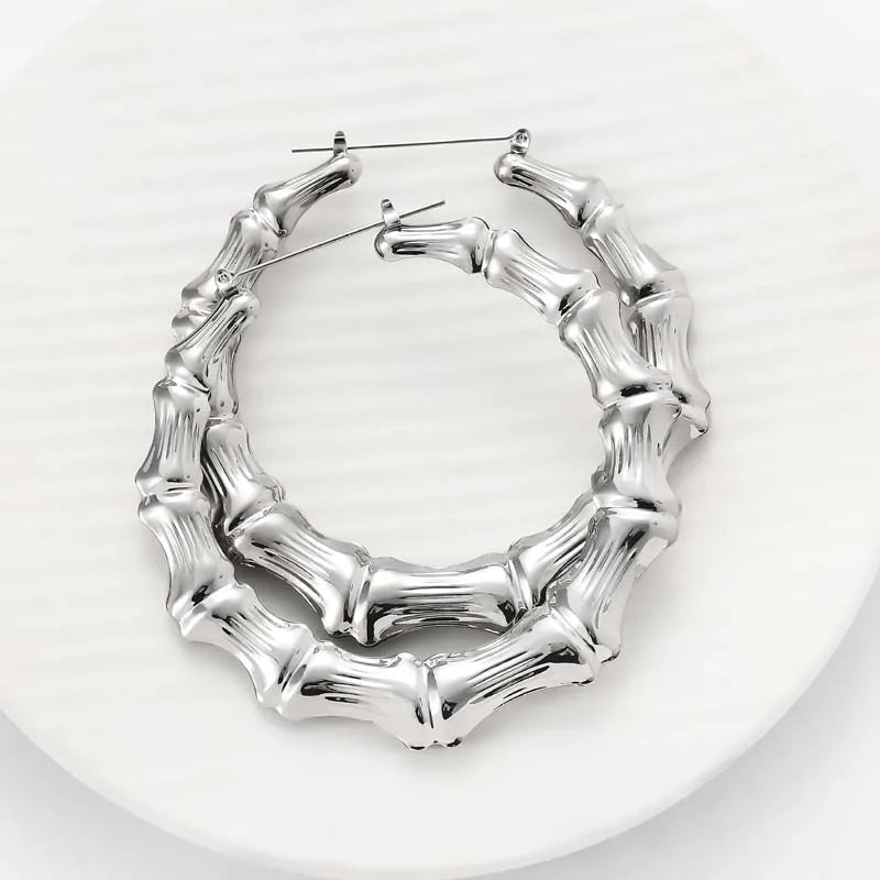 Silver bamboo hoop earrings with a textured, organic design displayed on a white surface.