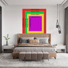 A bedroom featuring a bed with a headboard and a large framed art piece displaying various sized colored rectangles.