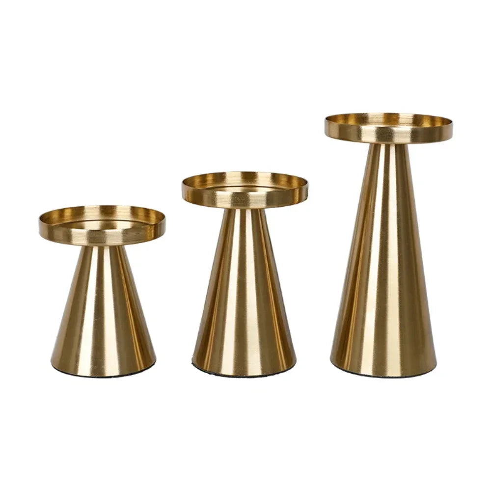 A set of three elegant gold metal candle holders with tapered bases and circular tops.