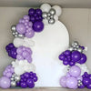 A large balloon arch display featuring dark purple and silver latex balloons against a white background.