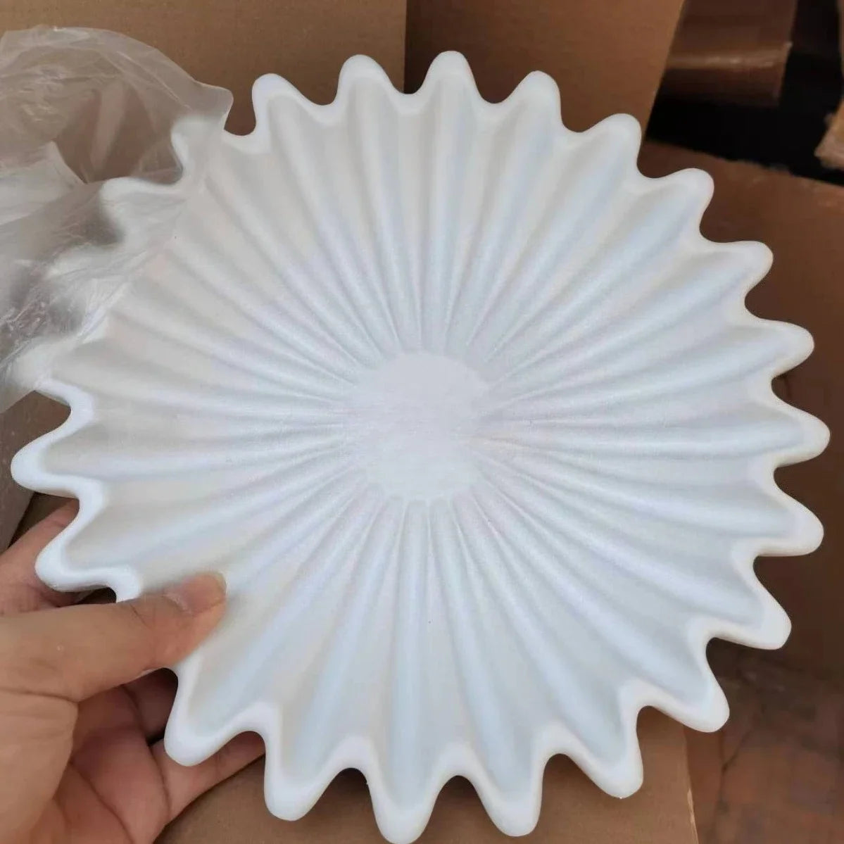 A white lotus leaf resin decorative bowl is held in a hand, showing its radiating petal design.