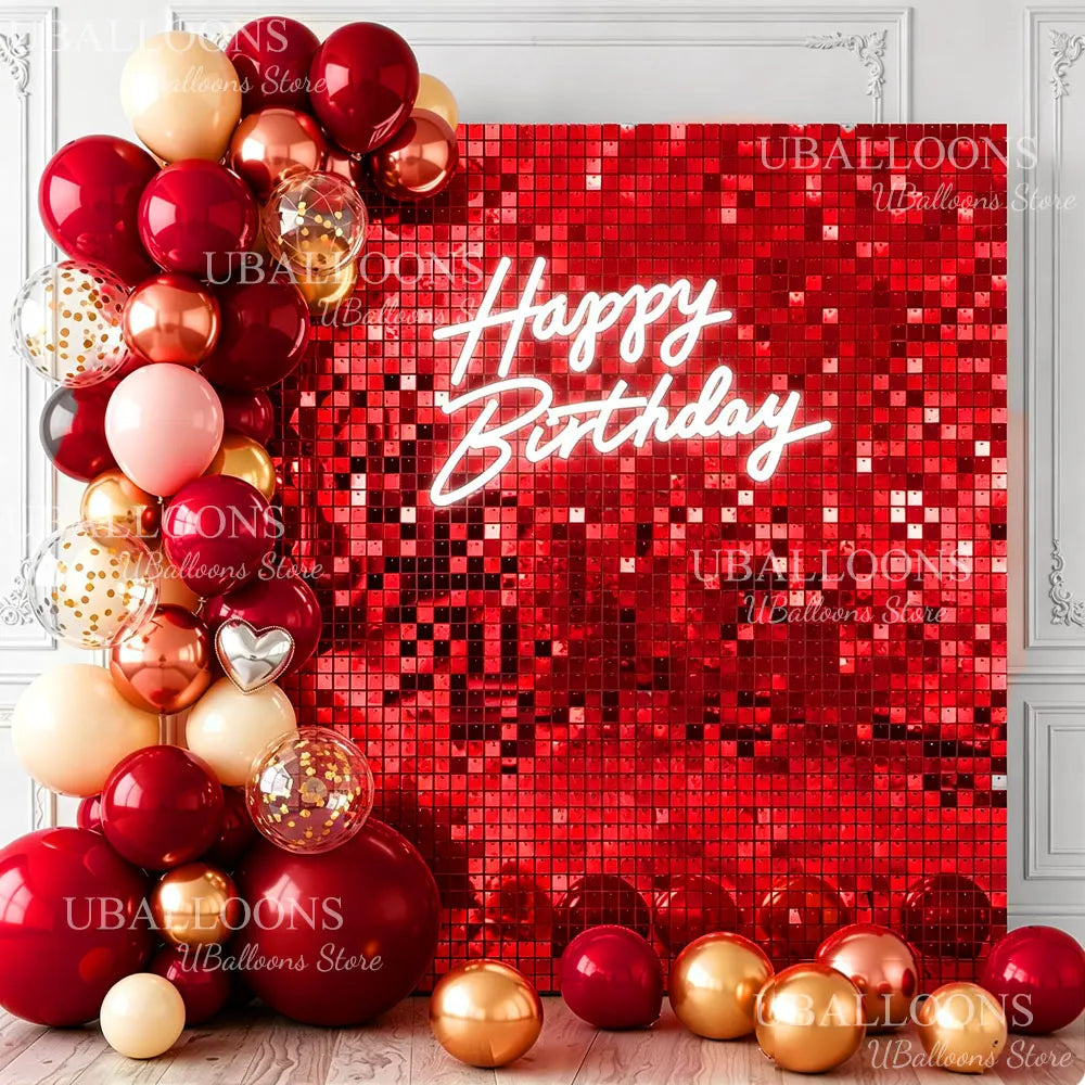 A red glitter wall backdrop decorated with balloons and a glowing Happy Birthday message.