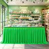 A bright green pleated polyester table skirt draped over a display table in a dessert area.