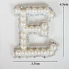 Alphabet letter E made of white pearls and rhinestones on clear fabric