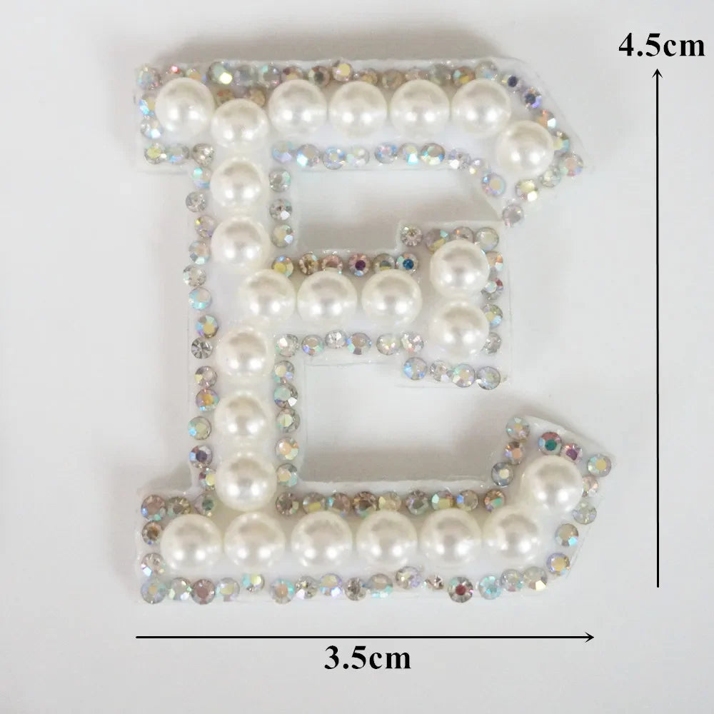 Alphabet letter E made of white pearls and rhinestones on clear fabric