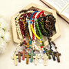 A wooden rosary beads necklace featuring various colored beads and Jesus crucifix pendants displayed in a wooden box.