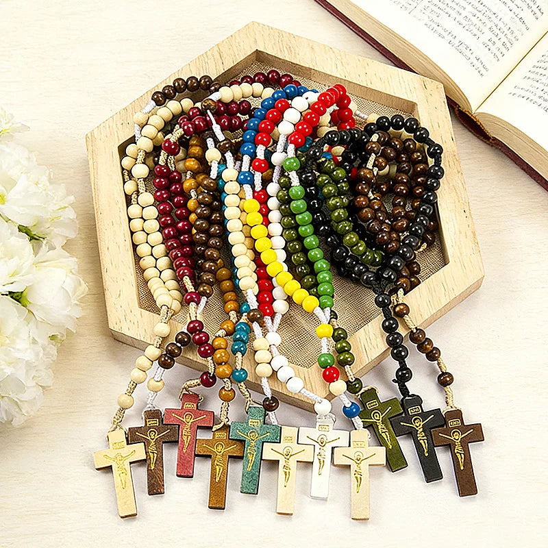 A wooden rosary beads necklace featuring various colored beads and Jesus crucifix pendants displayed in a wooden box.