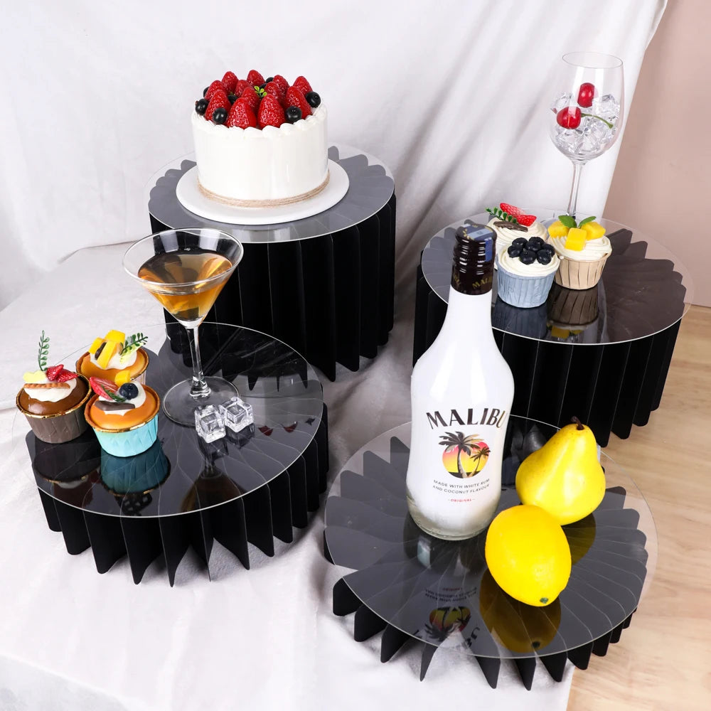 A set of five decorative black acrylic riser stands displaying various desserts and drinks.