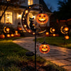 A black cat silhouette and an orange pumpkin moon are displayed on a garden stake light.
