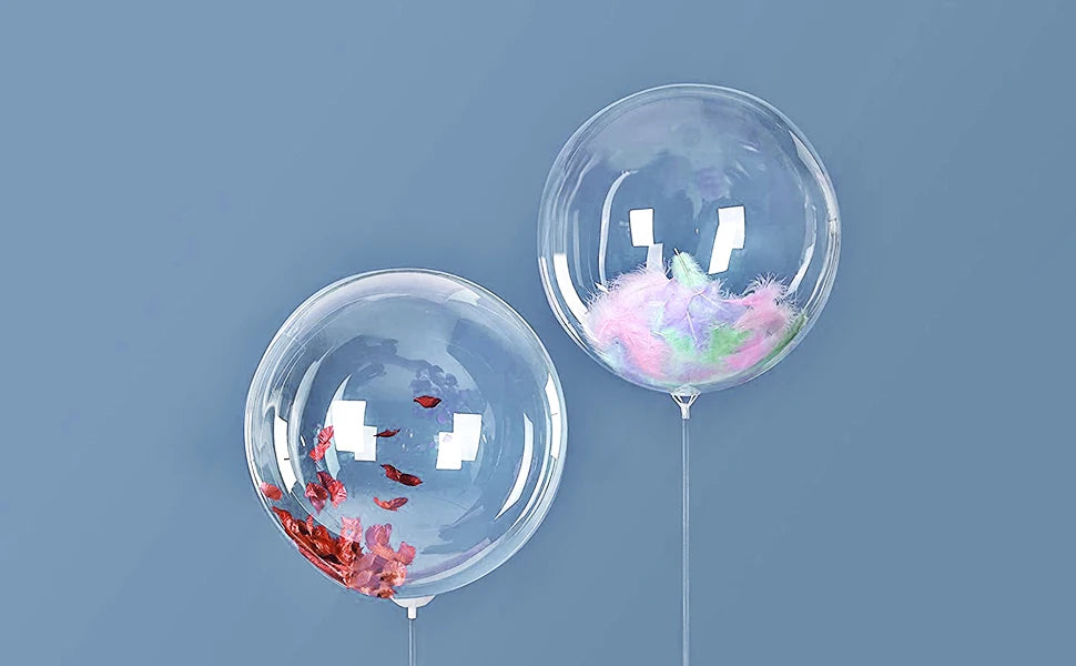 Two clear balloons filled with pink and green confetti float against a solid blue-gray background.