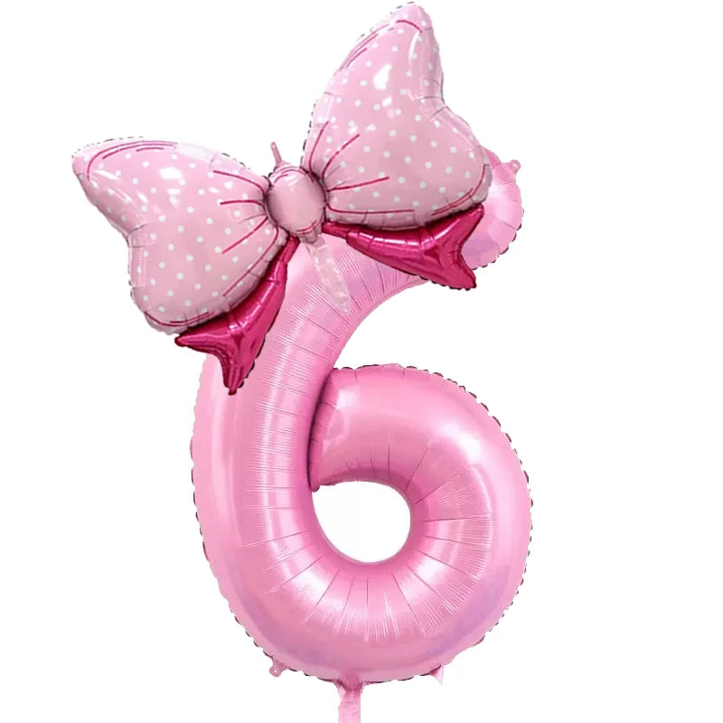 A pink foil balloon shaped like the number six with a large pink bow decoration.