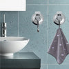 Silver suction cup hooks mounted on a tiled wall above a white vessel sink.