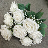 A bouquet of white silk peonies with green leaves and small white filler flowers.
