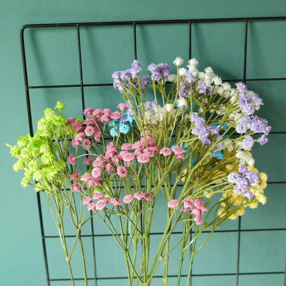 A bouquet of artificial gypsophila flowers in shades of purple, pink, and white against a dark grid background.