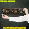 A hand holds a rustic wooden sign with the text STAY WEIRD, used as creative retro sign decoration.