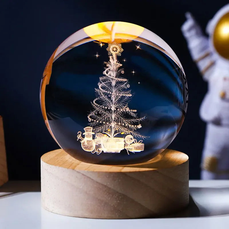 A crystal ball decoration featuring a laser engraved silhouette of a Christmas tree and stars against a dark blue background.