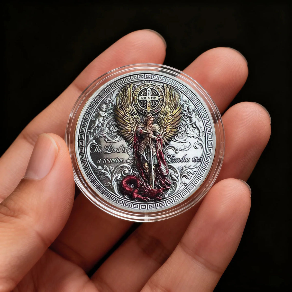 A clear coin featuring a depiction of Saint Michael the Archangel surrounded by wings and ornate design.