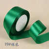 A roll of emerald green silk satin ribbon for gift wrapping and craft projects.