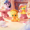 A collection of My Little Pony Magic Bottle collectible figurines in purple, pink, and yellow colors displayed on a light sur