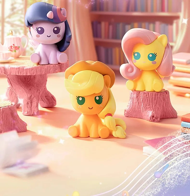 A collection of My Little Pony Magic Bottle collectible figurines in purple, pink, and yellow colors displayed on a light sur