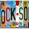 A vintage metal wall sign featuring the text ITS5OCLOCKSOMEWHERE in various colors and fonts.