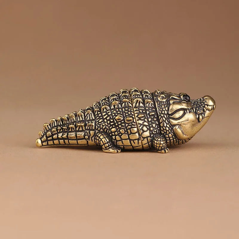 Antique brass crocodile figurine with detailed texture, displayed on a neutral background.