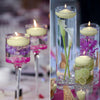 A set of twelve ivory soy wax floating candles in various glass holders, some with floral accents.