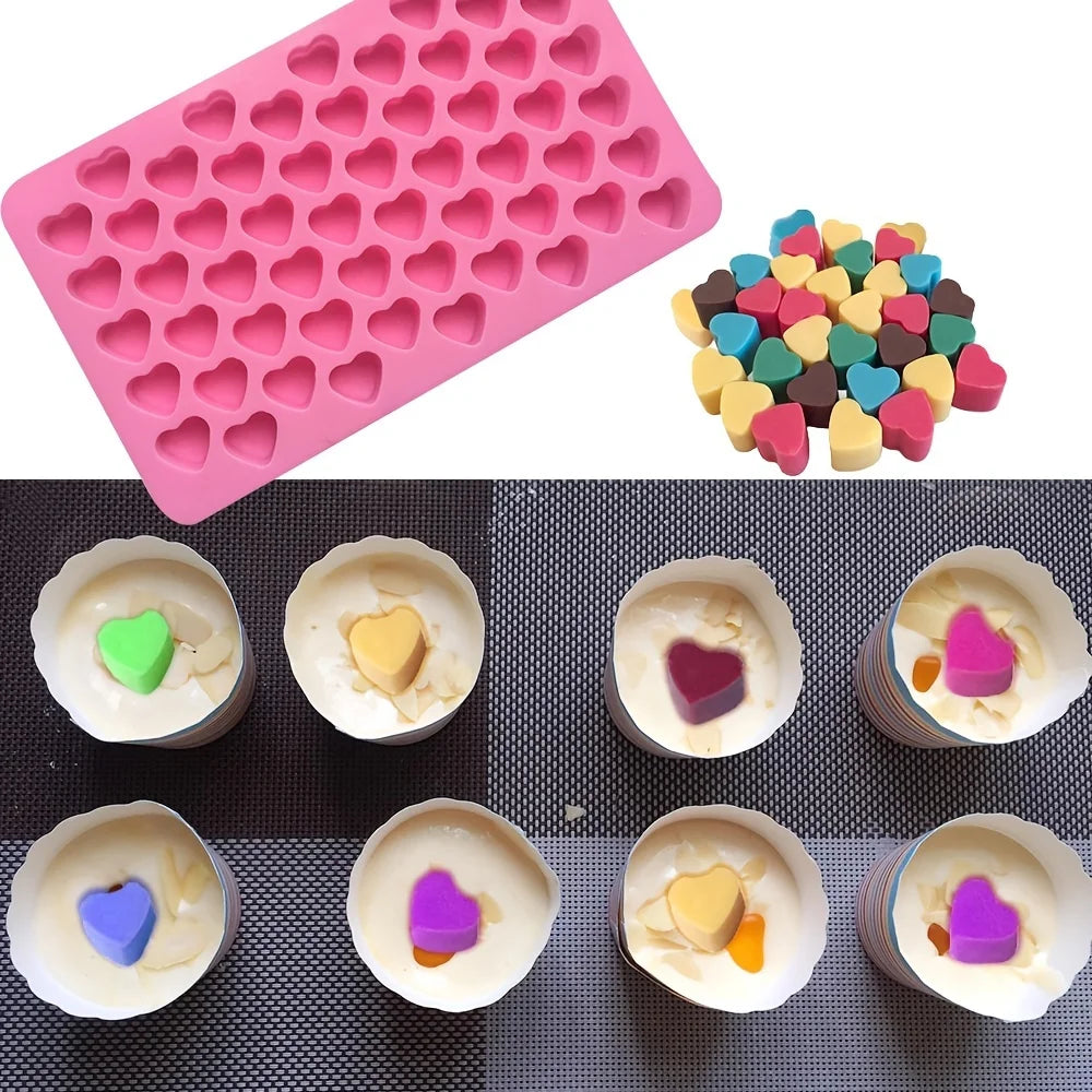 A pink silicone mold tray with hemispherical cavities and a colorful assortment of silicone candy molds.