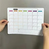 A magnetic fridge planner grid showing days of the week for monthly planning.