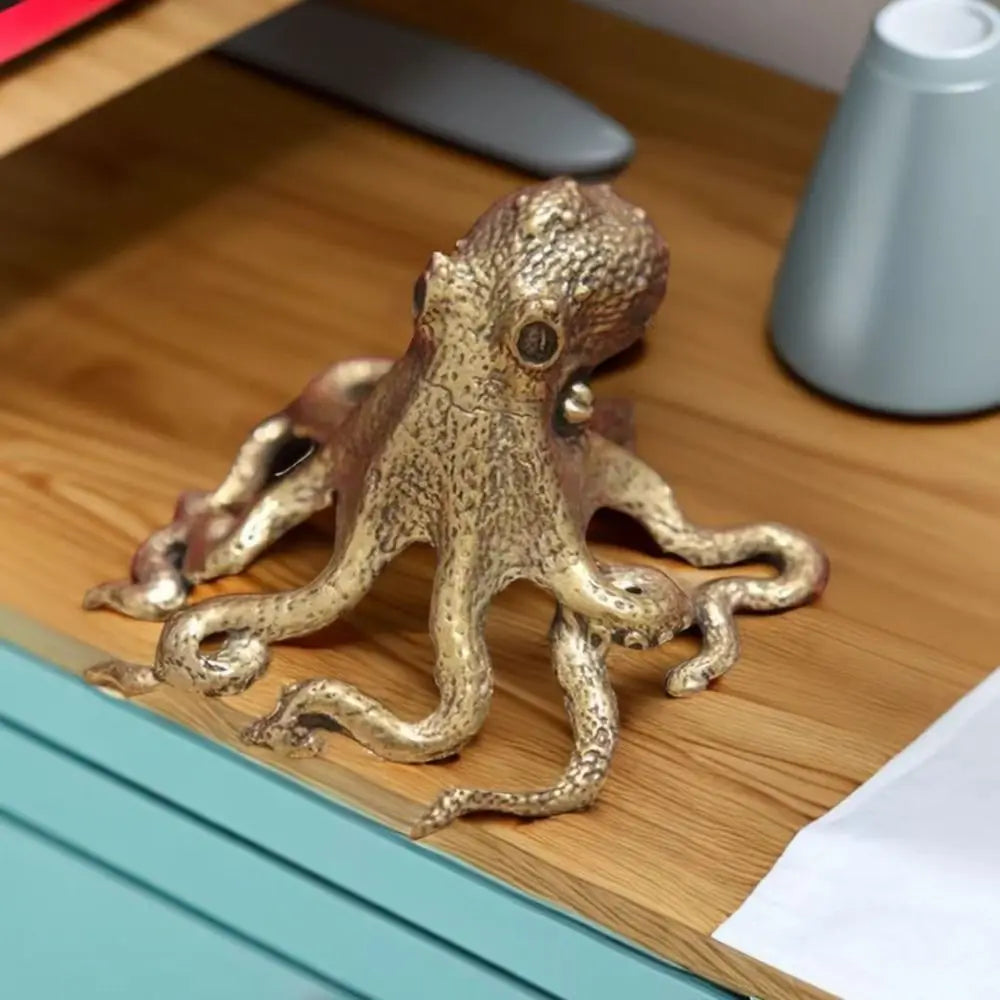 Antique brass octopus desk ornament with textured body and tentacles resting on a wooden surface.