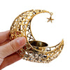 A hand holds a gold metallic crescent moon candle holder with a star charm.