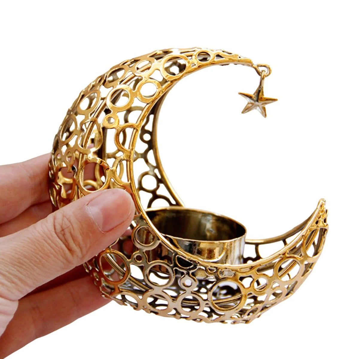 A hand holds a gold metallic crescent moon candle holder with a star charm.