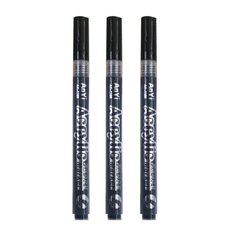 Three black acrylic paint pens standing vertically in a row.
