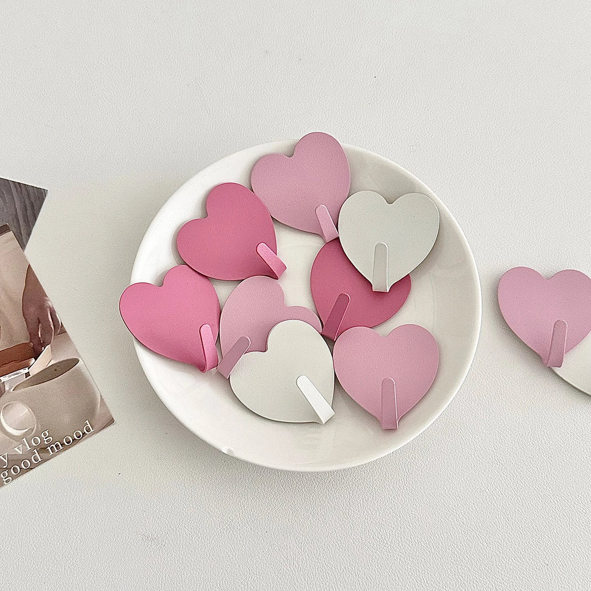 A set of pink and white heart-shaped adhesive key hooks for various rooms.
