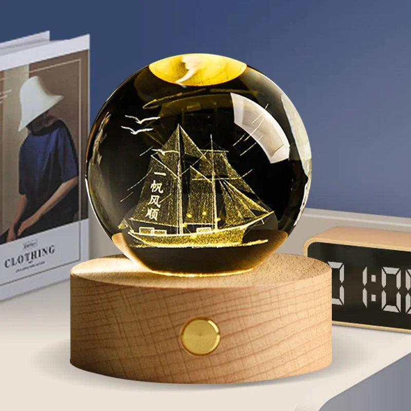 A black crystal ball decoration with a golden interior showing a silhouette of a sailing ship.