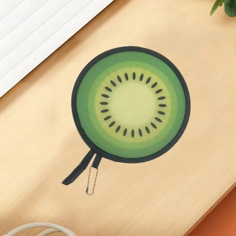 A round foldable hand fan with a green fruit design resting on a light wooden surface.