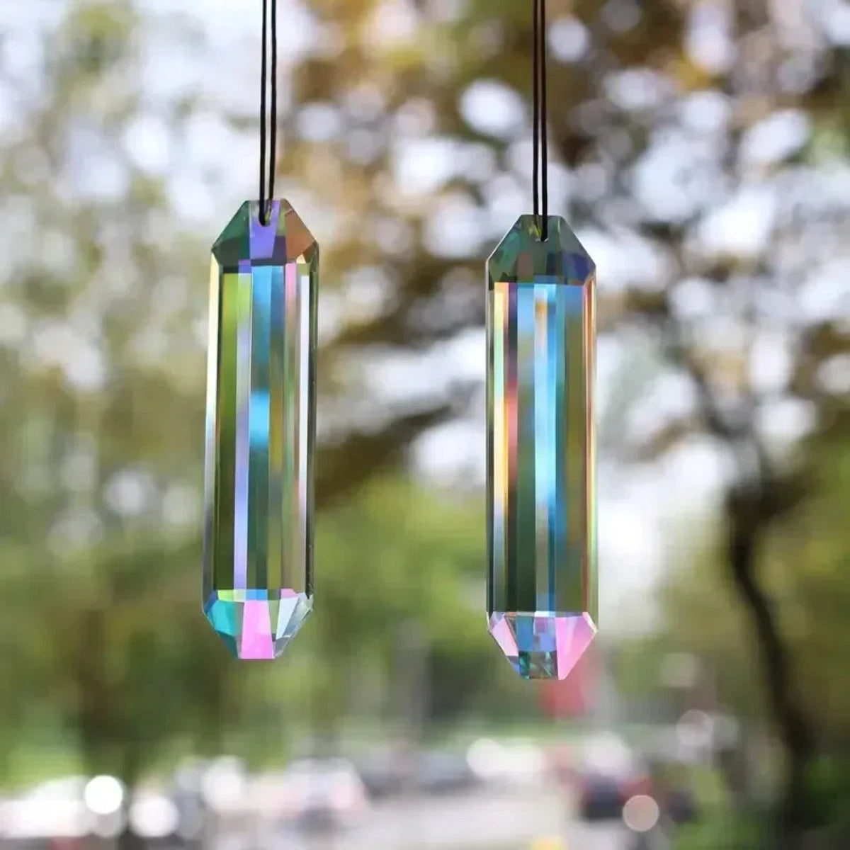 A pair of iridescent crystal pendants hanging, catching and refracting light.