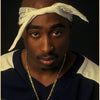 A man wearing a white cloth headband and gold chain looking directly at the camera.
