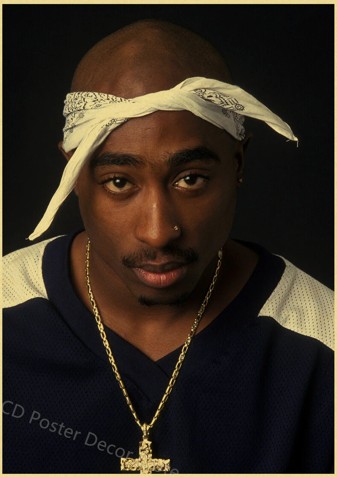A man wearing a white cloth headband and gold chain looking directly at the camera.